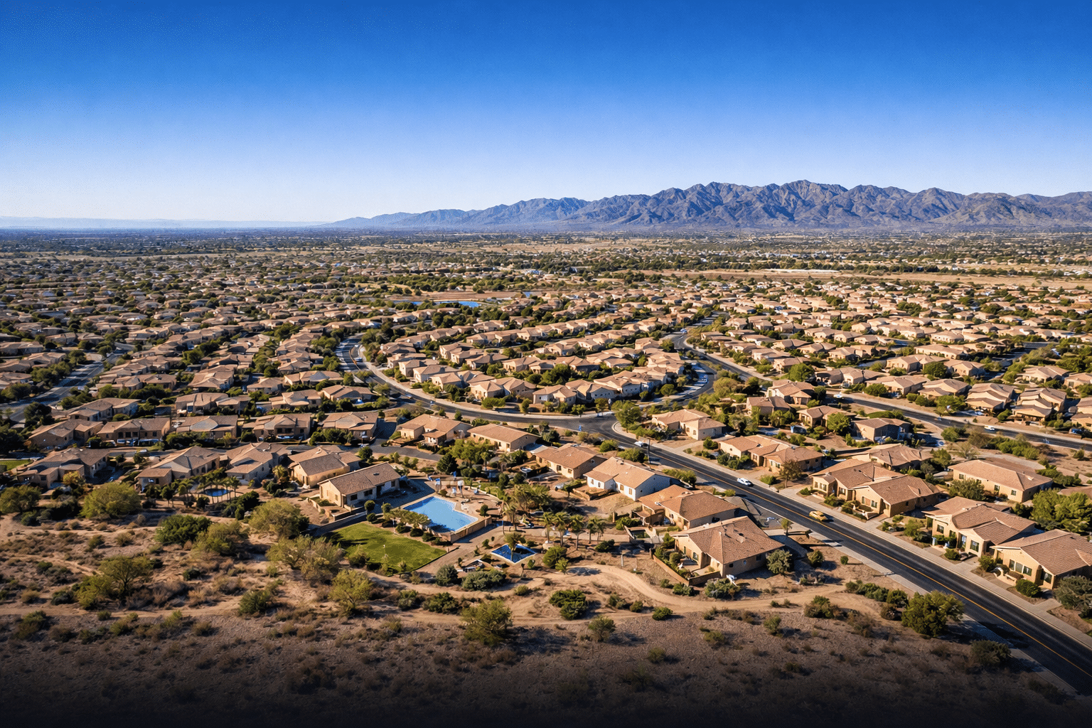Aerial view of a Chandler Arizona master-planned community with curving streets and terracotta rooftops at late morning — West USA Realty